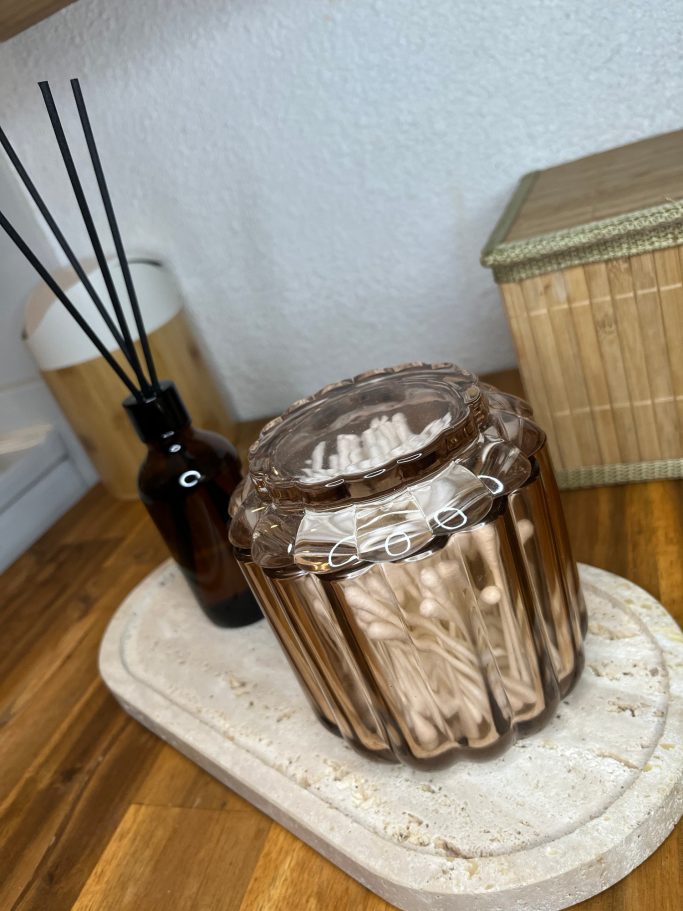 Détail mise en scène Pot en verre fumé et diffuseur sur plateau décoratif en pierre claire